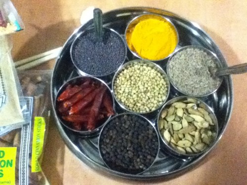Clockwise starting with the yellow stuff: turmeric, cumin seed, green cardamom, black peppercorn, dried red chilies, black mustard seed; center is coriander seed. 