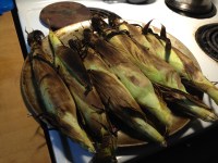 Half dozen ears of butter and sugar corn, cooked in their natural wrappings under a broiler.